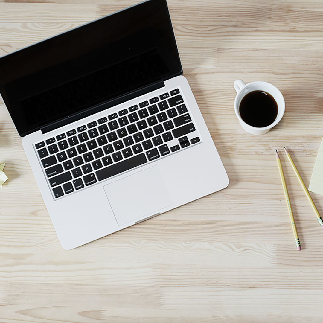 bureau avec un ordinateur une tasse à café et des crayons